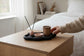 Solace & Smoke Lunar Tray in black Jesmonite, holding a pink diffuser and a brown candle.